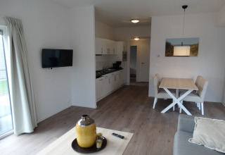 Moderne woonkamer en keuken in het Breeduyn Village 3 lodge in België, met lichte inrichting.