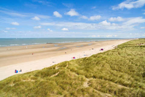 Strandzicht vanaf de lodge Breeduyn Village 3 in België met zandduinen, zee en blauwe lucht.