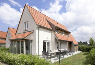Moderne lodge met rood pannendak en terras in Breeduyn Village 3, België, op een zonnige dag.