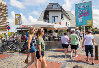 Mensen lopen langs een terras bij Breeduyn Village 3 op een zonnige dag in België.