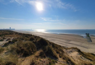 Zonnig strandzicht vanaf de duinen bij Breeduyn Village 3 in België, met uitzicht op zee en kustlijn.