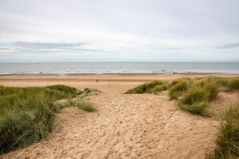 Uitzicht vanaf de duinen bij Breeduyn Village 3 lodge in België, op een zandstrand en rustige zee.