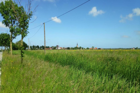 Uitzicht op groene velden en een dorp vanaf Breeduyn Village 3 in België onder een heldere lucht.