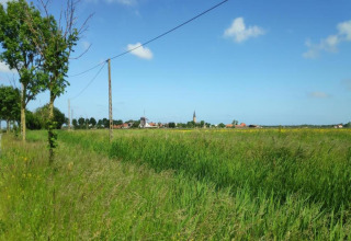 Uitzicht op groene velden en een dorp vanaf Breeduyn Village 3 in België onder een heldere lucht.