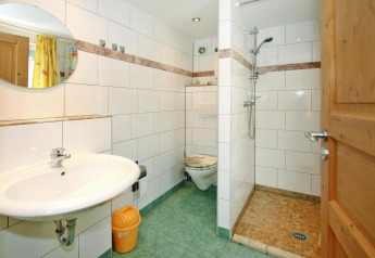 Baño luminoso del Bungalow '35 qm 2 Pers' en Alemania con ducha, inodoro y azulejos verdes.