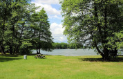 Lush lawn with picnic bench and lake view surrounded by trees at Holiday home 'Susanne' in Germany.