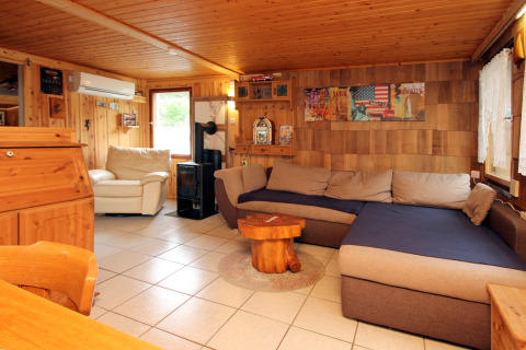 Soggiorno accogliente con pannelli in legno, divano angolare e poltrona a Holiday home Susanne in Germania.