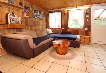 Cozy living room with sectional sofa and wooden decor at Holiday home Susanne 58 qm in Germany.