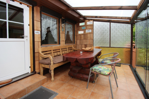 Véranda en bois couverte, table rustique sculptée, banc, chaises et décorations de plaques d'immatriculation.