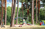 Parque infantil al aire libre en un bosque con columpio, arenero y tobogán en Bungalow «50 qm 5 Pers».