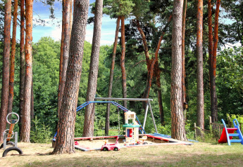 Parque infantil al aire libre en un bosque con columpio, arenero y tobogán en Bungalow «50 qm 5 Pers».