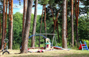 Speelplein in het bos met schommel, zandbak en glijbaan bij Bungalow «50 qm 5 Pers» in Duitsland.