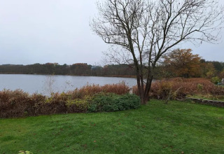 Zicht op meer met gras en bomen aan Bungalow «50 qm 5 Pers» in Duitsland tijdens de herfst.