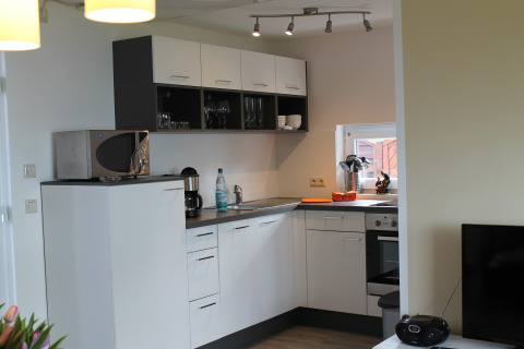 Moderne keuken met witte kasten, magnetron, koffiezetapparaat en raam in een lodge in Duitsland.