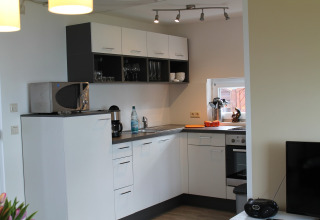 Moderne keuken met witte kasten, magnetron, koffiezetapparaat en raam in een lodge in Duitsland.