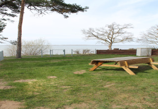 Uitzicht op zee vanaf het grasveld bij lodge 'Am Strand' in Duitsland met houten tafel en bomen.