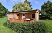 Bungalow in legno con terrazza nel complesso Gänseblümchen 6 in Germania, immerso nel verde.