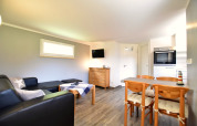 Contemporary living room at Bungalow complex «Gänseblümchen 6» with dining and kitchen area in Germany.