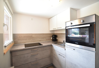 Cucina moderna con mobili grigi, forno incassato, piano cottura, macchina da caffè e finestra in Germania.