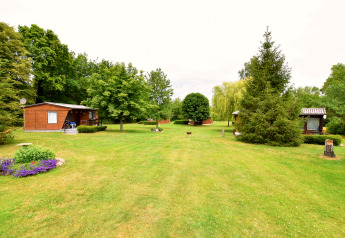 Photo d’un site de glamping avec cabanes en bois, pelouse bien entretenue et de nombreux arbres.