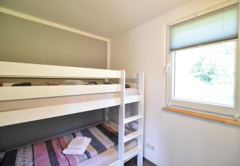 Lichte kamer met stapelbedden en een raam in Bungalowcomplex Gänseblümchen 6 in Duitsland.