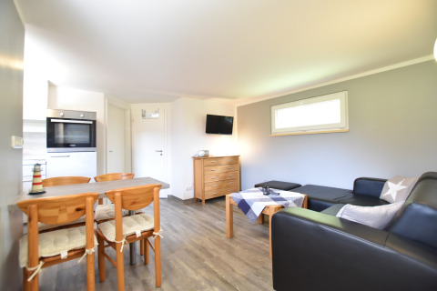 Bright, modern living room at Bungalow complex “Gänseblümchen 6” in Germany, with dining and lounge areas.