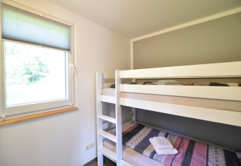 Kamer met stapelbed en raam in bungalowcomplex 'Gänseblümchen 6' in Duitsland.