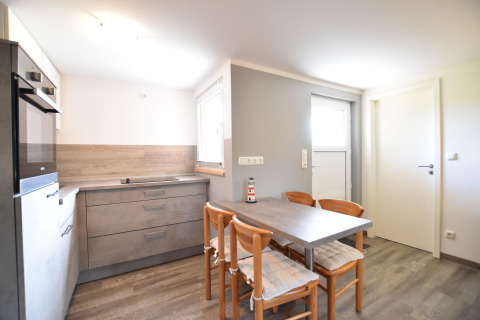 Lyst køkkenområde med grå skabe, spisebord til fire og moderne indretning i Bungalow Gänseblümchen 6.