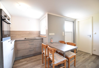 Bright kitchen with modern grey cabinets, a dining table for four in Bungalow complex Gänseblümchen 6, Germany.
