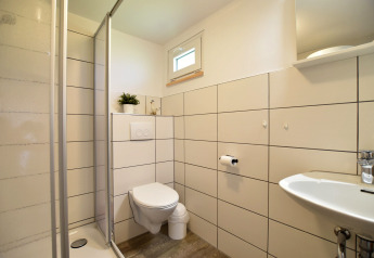 Modern bathroom at Bungalow complex Gänseblümchen 6 in Germany, featuring a shower, wall toilet, and sink.