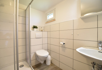 Moderne badkamerruimte in Bungalowcomplex Gänseblümchen 6, Duitsland, met douche en wandtoilet.