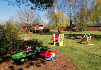 Playground with swings, slide and toy cars in the garden at Bungalow complex Gänseblümchen 6 in Germany.