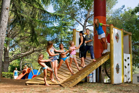 Children playing together at a playground in Camping Brioni, a holiday park in Istria, Croatia, surrounded by trees.