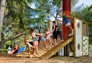Children playing together at a playground in Camping Brioni, a holiday park in Istria, Croatia, surrounded by trees.