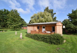 Wooden lodge at Bungalow complex Gänseblümchen 6, surrounded by green lawn and trees in Germany.
