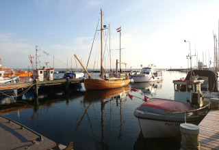 Barcos atracados en un puerto soleado, vistos desde un alojamiento glamping con vistas al puerto.