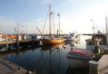 Boats docked at the marina on a sunny day, seen from a glamping accommodation with scenic harbor views.
