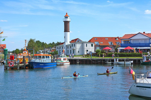 Haven met boten en kajakkers bij het bungalowcomplex Gänseblümchen 6 met een vuurtoren, Duitsland.