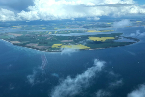 Luchtfoto van een mooi eiland met velden en kustlijn, gezien vanuit een glamping verblijf.