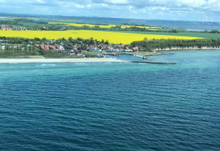 Seaside view from Bungalow complex Gänseblümchen 6 in Germany with ocean, white beach and colorful fields.