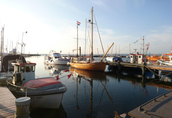 Harbor scene at a glamping accommodation with various boats moored, calm water and clear skies.