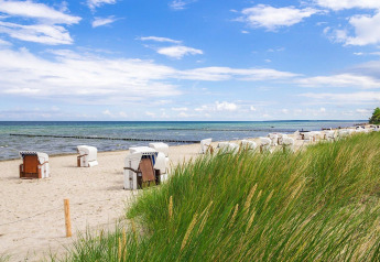 Scenic beach with traditional beach chairs and grassy dunes at Bungalow complex Gänseblümchen 6, Germany.