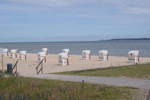 Genummerde strandstoelen aan het zandstrand bij Bungalowcomplex Gänseblümchen 6 in Duitsland.