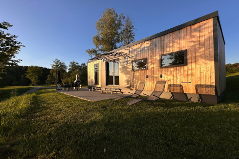 Vista soleggiata su una tiny house in legno con sdraio a Holiday village SEEBLICK, Eixendorfer See.