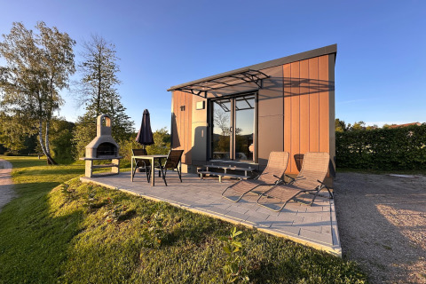 Modern tiny house Holiday village SEEBLICK with patio and grill at Eixendorfer See in sunny weather.