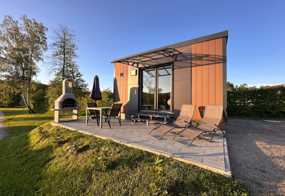 Moderne tiny house Holiday village SEEBLICK med terrasse og grill ved Eixendorfer See i solskin.