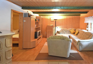 Gezellige woonkamer met houten lambrisering, hoekbank, fauteuil en tv in lodge Neustadt, Duitsland.
