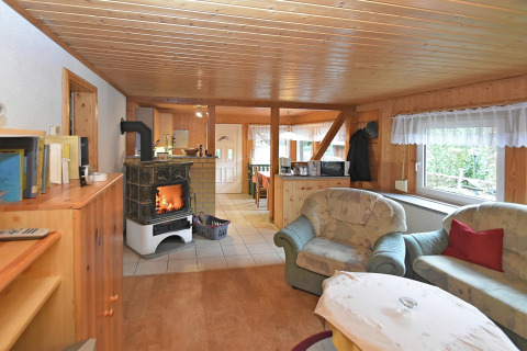 Gezellige chalet living in Duitsland met houtkachel, comfortabele zetels en zicht op de tuin.