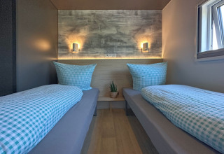 Moderne soveværelse i et tiny house med to enkeltsenge, lyseblåt sengetøj og naturligt lys fra vinduet.