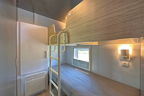 Moderne tiny house slaapkamer met stapelbedden, een raam, wandlamp en compacte opbergkast overdag.
